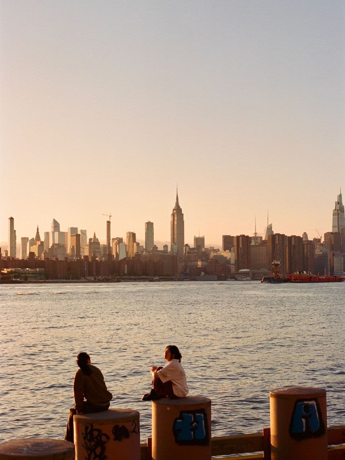 Two people on the waterfront watching the Manhattan skyline at sunset