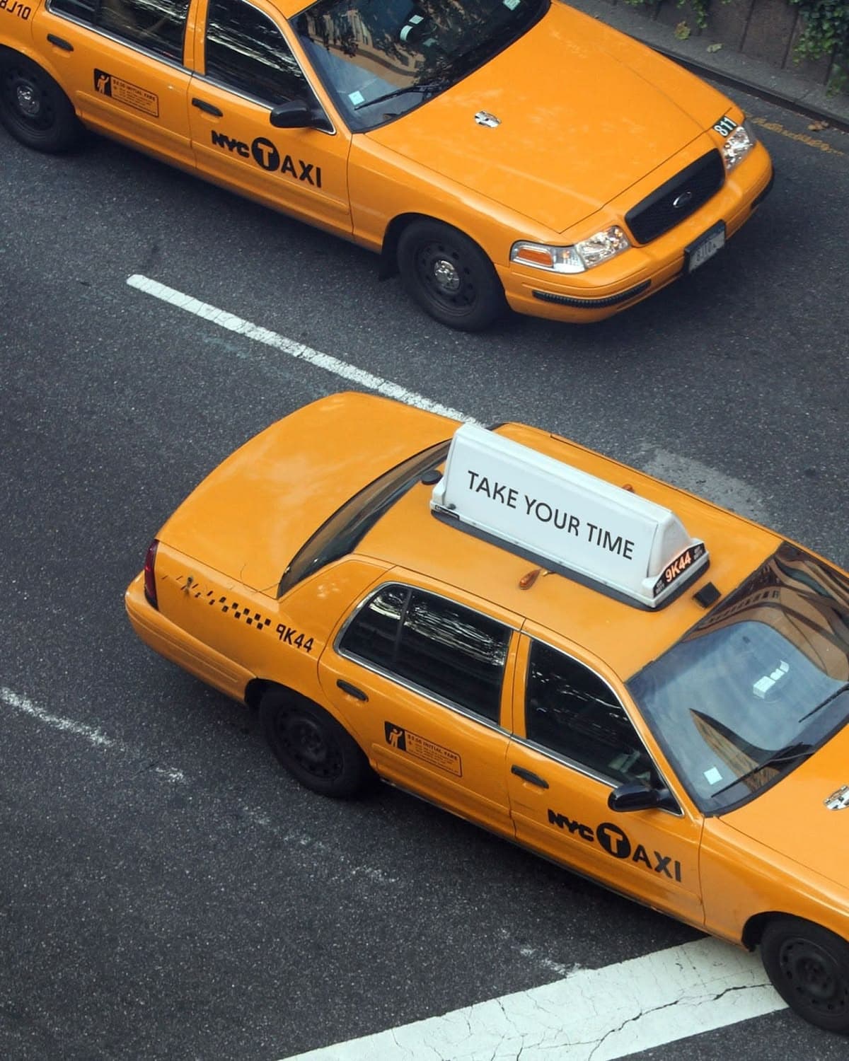 Two yellow cabs crossing an intersection from above